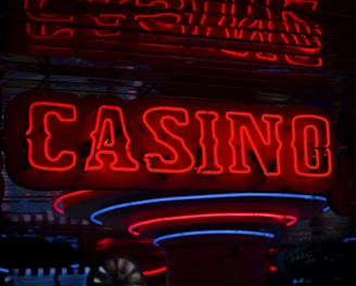 Neon lights display the word 'CASINO' in bright red, standing out against a dark background. The vibrant glow reflects a lively and bustling atmosphere.