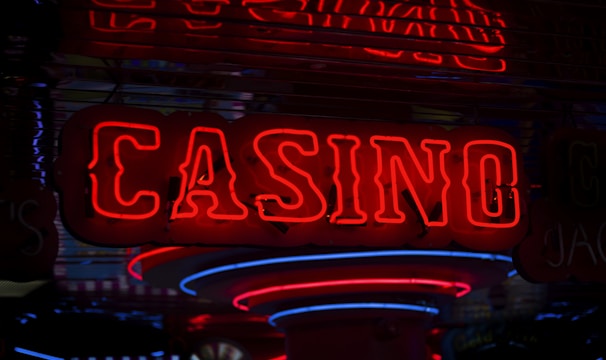 Neon lights display the word 'CASINO' in bright red, standing out against a dark background. The vibrant glow reflects a lively and bustling atmosphere.